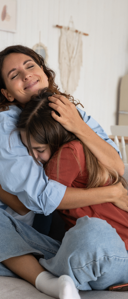 Parent and child sharing a warm, supportive hug in a calming home environment, representing the emotional safety and trusting relationships prioritized at TFT Clubhouse.